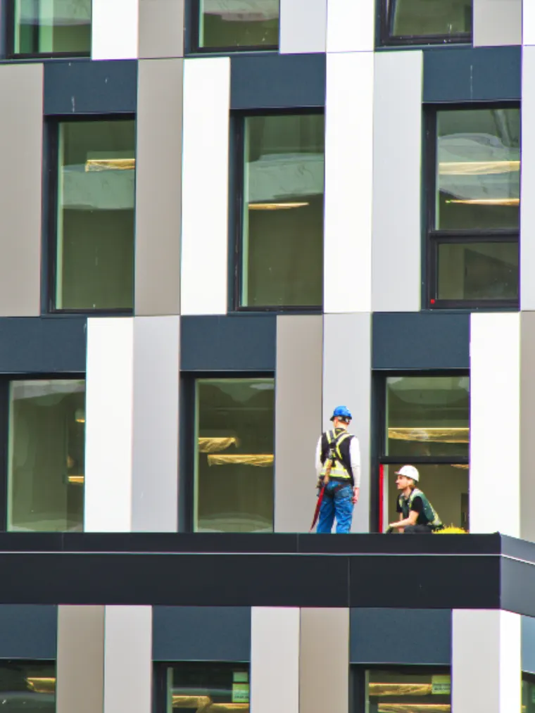 Two workers on a low-slope roof behind a parapet wall