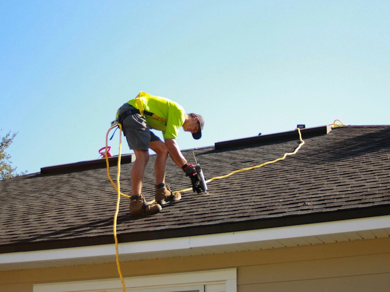 A roofer working on an asphalt shingle slope